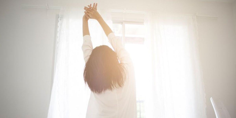 person doing a simple morning stretch near window as part of daily healthy habits